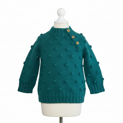 Blue knitted sweater with polka dots on a mannequin against a white background