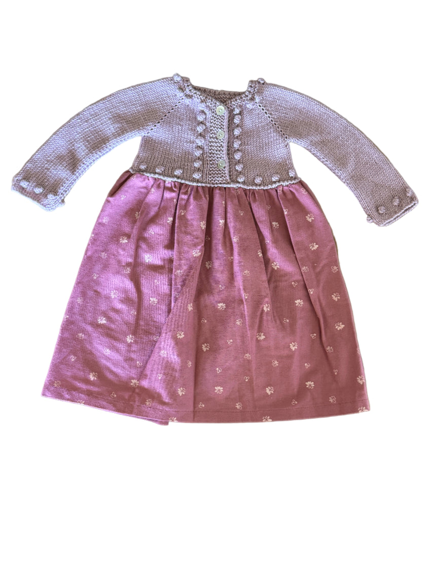 Pink dress with white embroidery on a wooden surface
